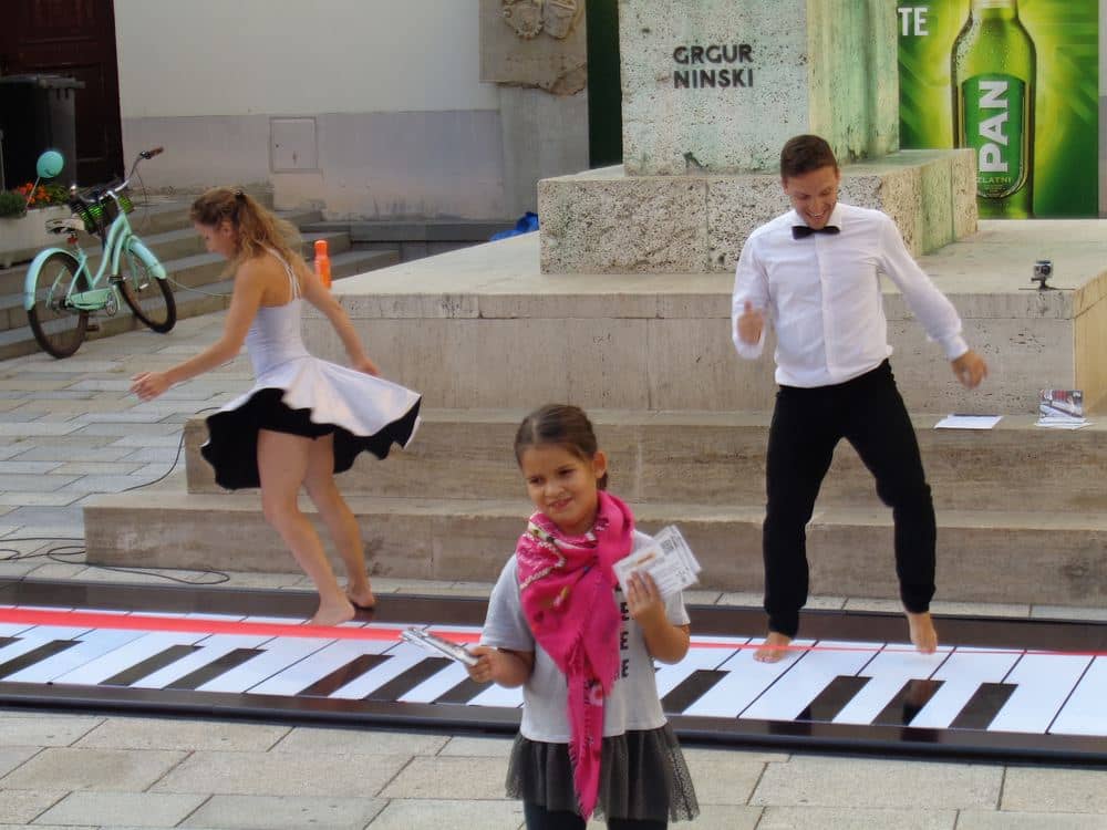 Children playing a giant floor keyboard with their feet at Špancirfest