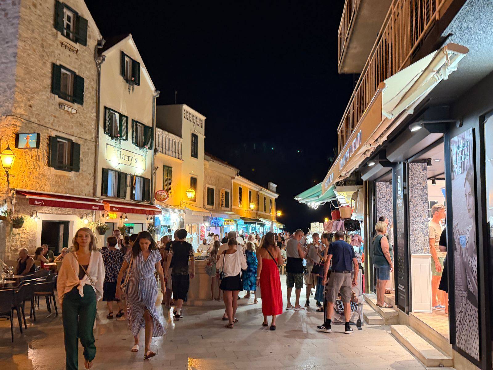 Abendlicher Korso in einer Gasse von Vodice, Menschen zwischen Restaurants und Laeden