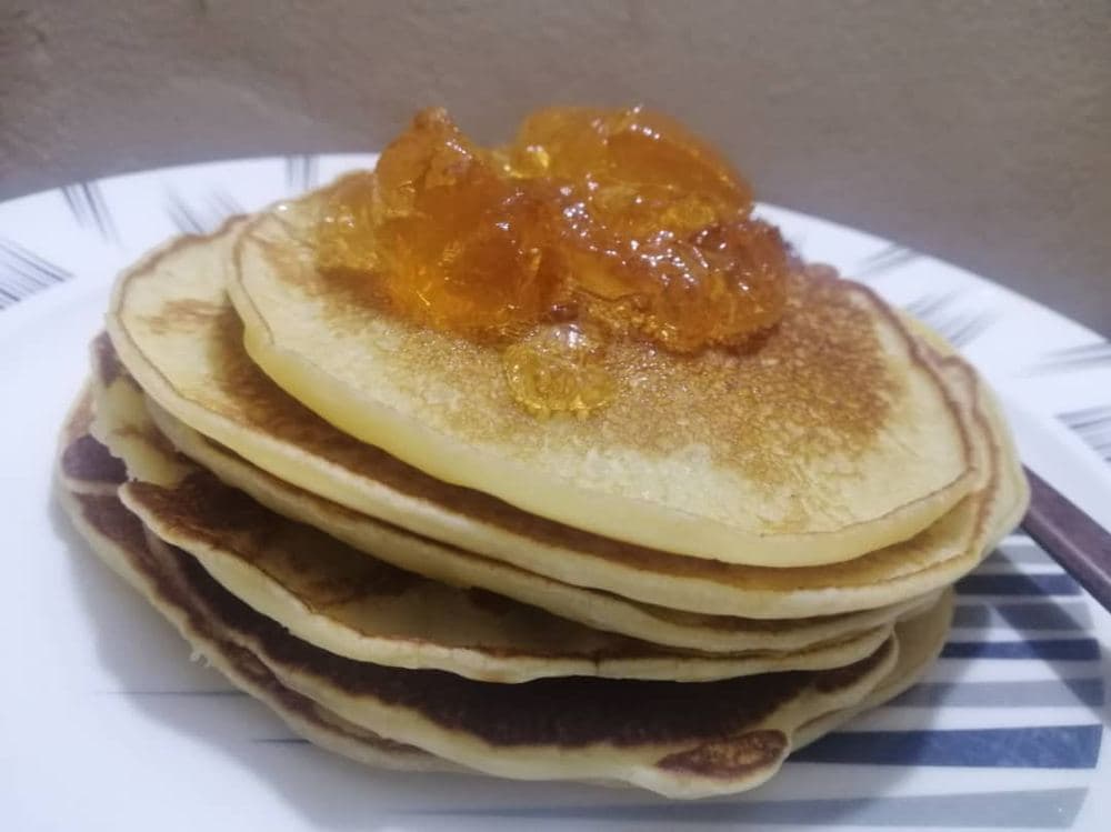 Ein Stapel dicker Pfannkuchen mit Fruchtmarmelade obenauf