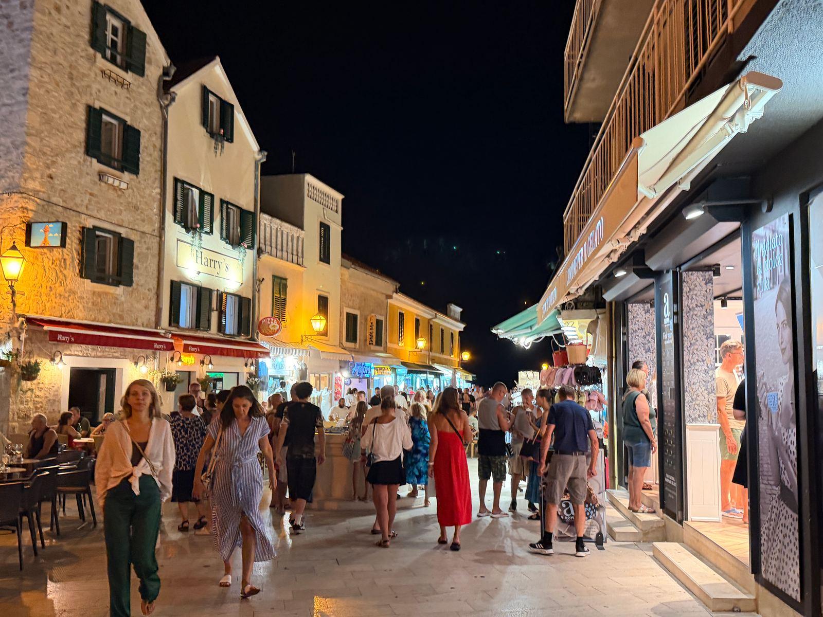 Abendlicher Korso in einer Gasse von Vodice, Menschen zwischen Restaurants und Laeden