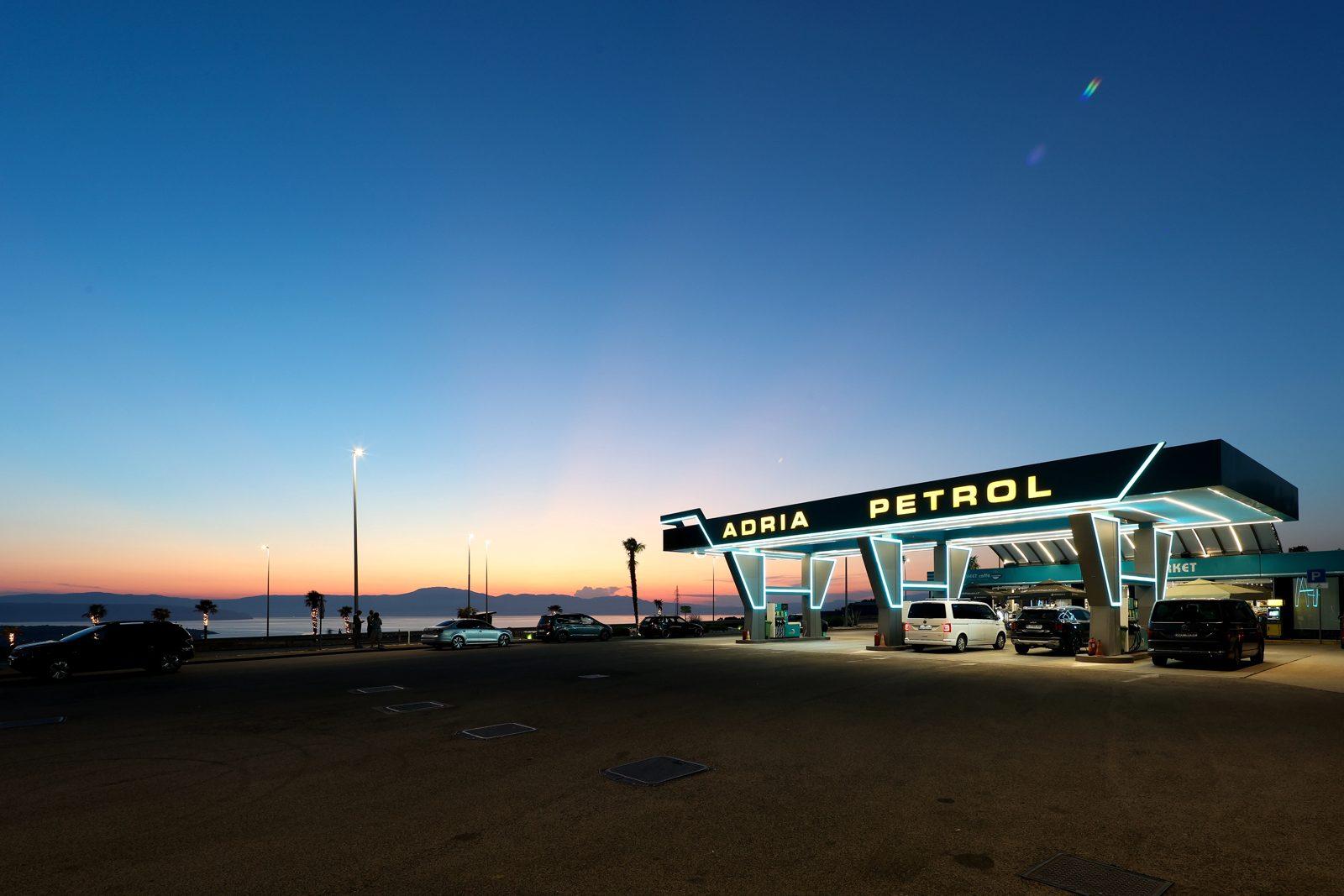 Adria Petrol at sunset seen from the forecourt, neon canopy and the Kvarner Bay behind