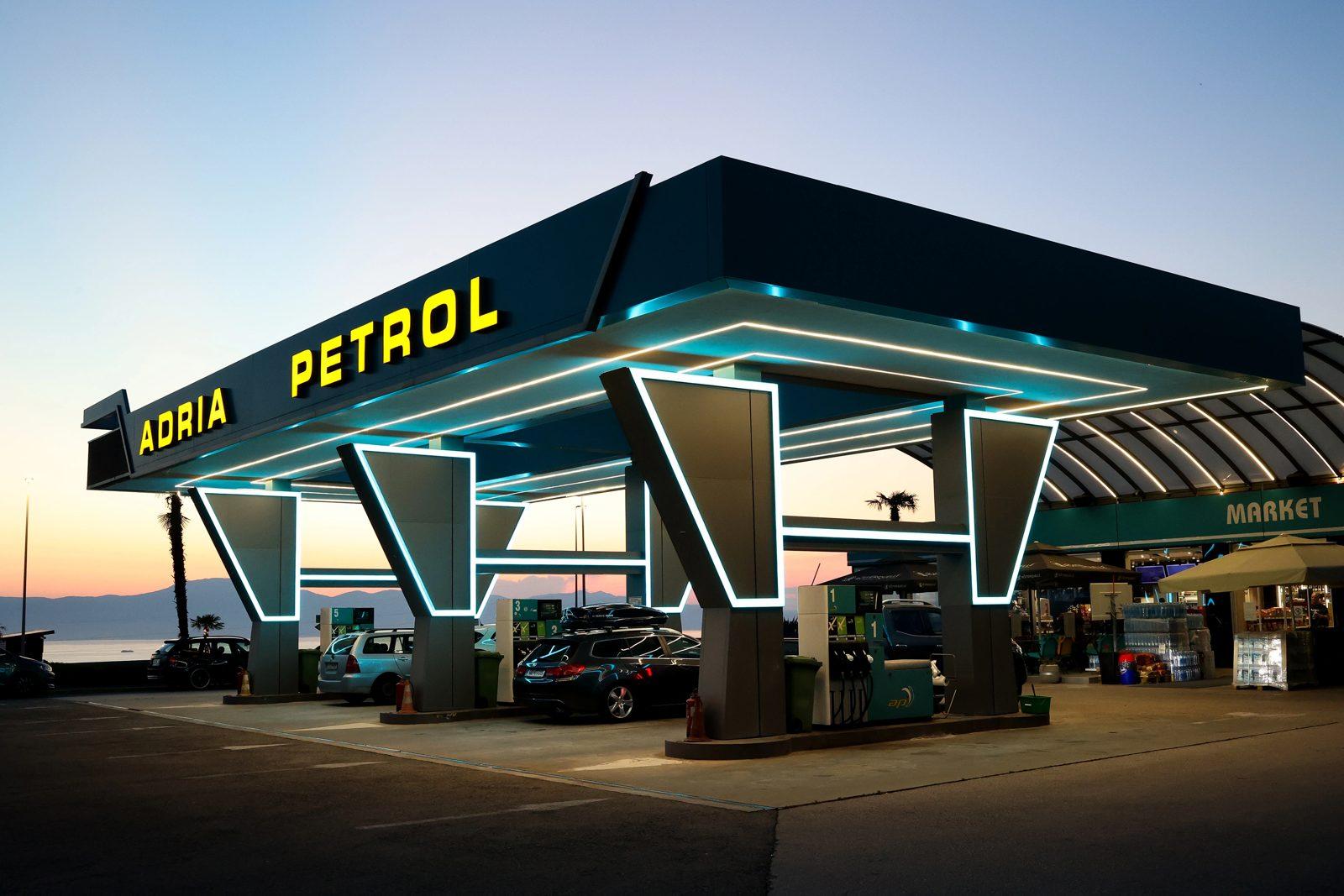 Fuel pumps under the neon canopy of Adria Petrol at dusk