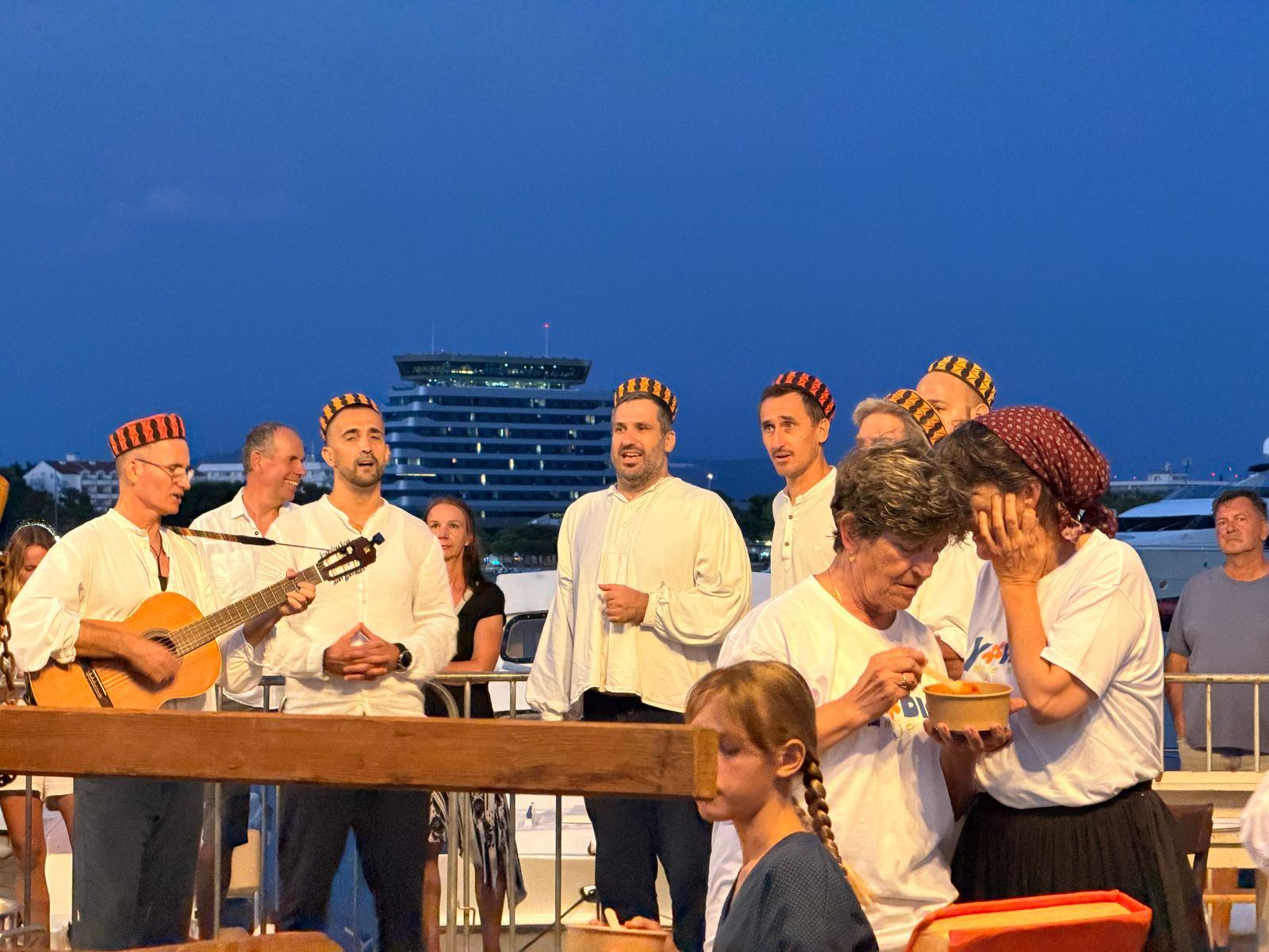 Klapa-Sänger in weißen Hemden am Kai von Vodice, daneben wird šaša mit Polenta ausgegeben